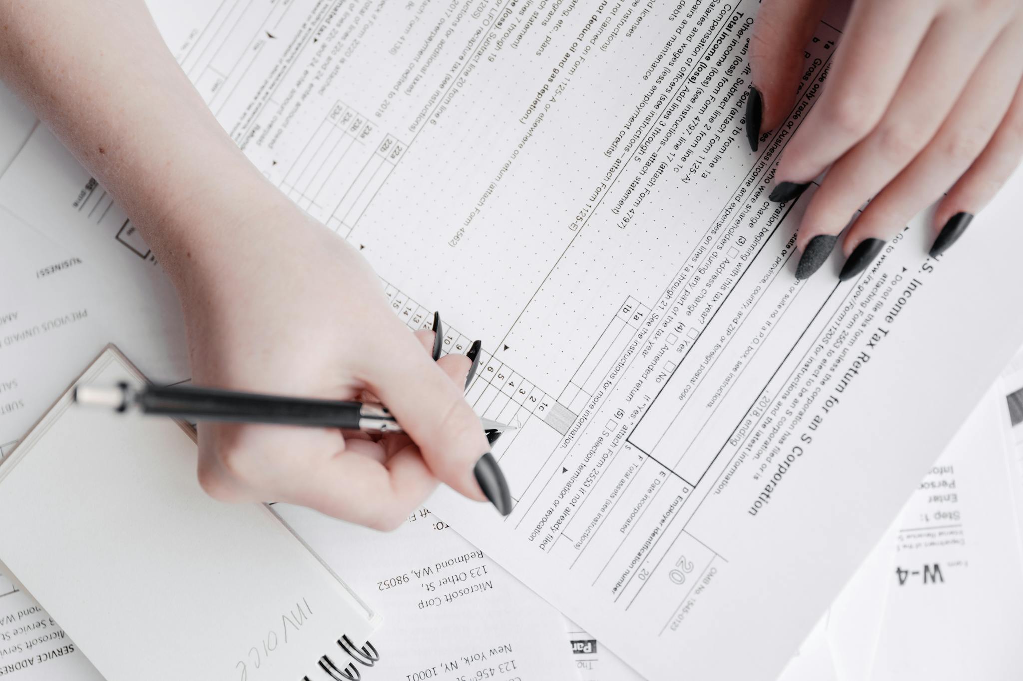 A detailed close-up of a woman filling out tax forms with a pen. Ideal for finance themes.